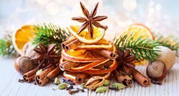 Stroik świąteczny z plastrów pomarańczy, laski cynamonu i anyżu w gwiazdki.