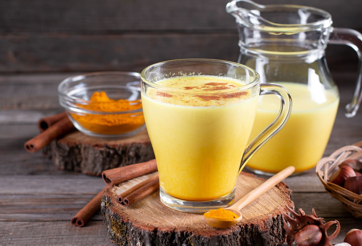 Napój złote mleko w szklance i dzbanku na stole. 